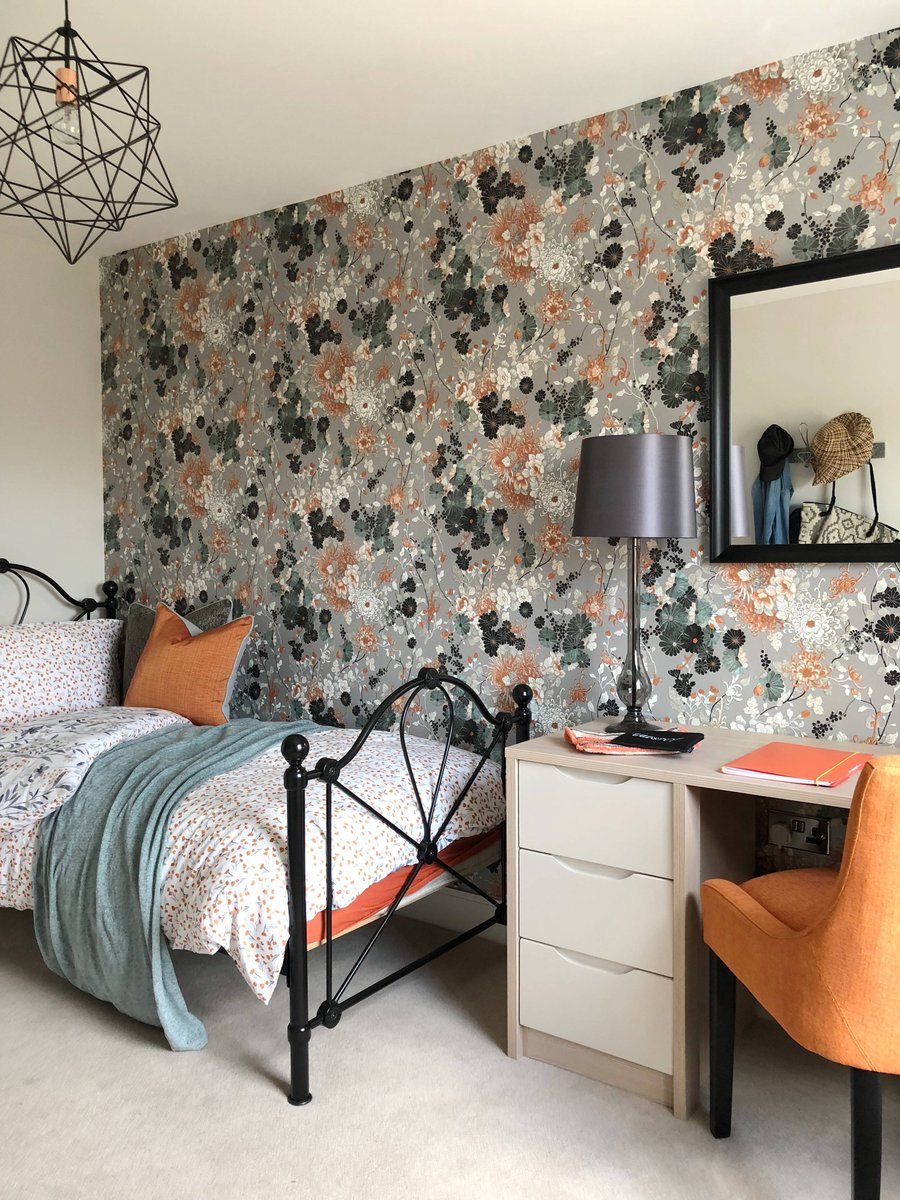 اتاق خواب با تخت تک نفره و میز کار که از ترکیب کاغذ دیواری گلدار زیبا و دیوارهای سفید رنگ در آن استفاده شده است